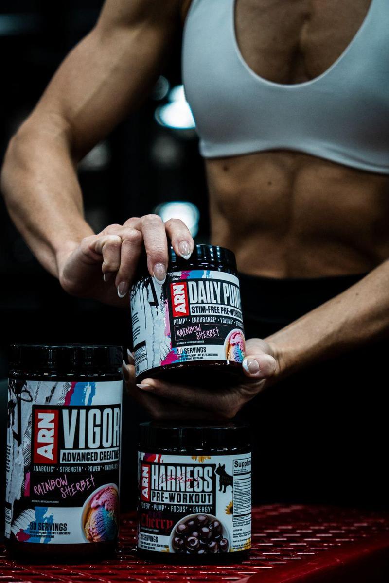 Athlete stacking ARN supplement tubs on a red gym bench