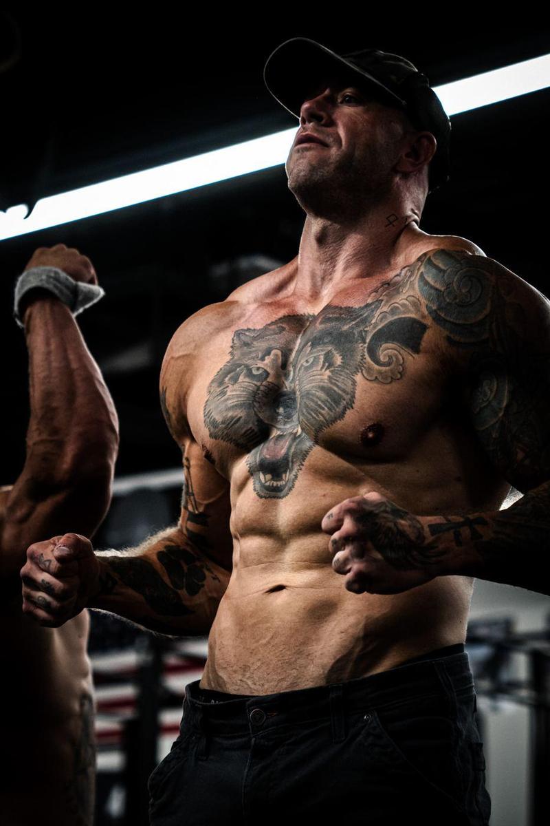 Tattooed bodybuilder flexing, a wolf tattoo across his chest