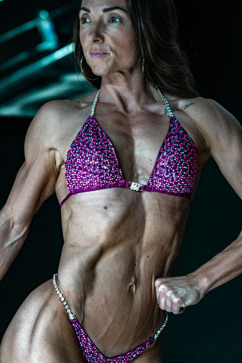 Female competitor in a crystal suit hitting a front pose